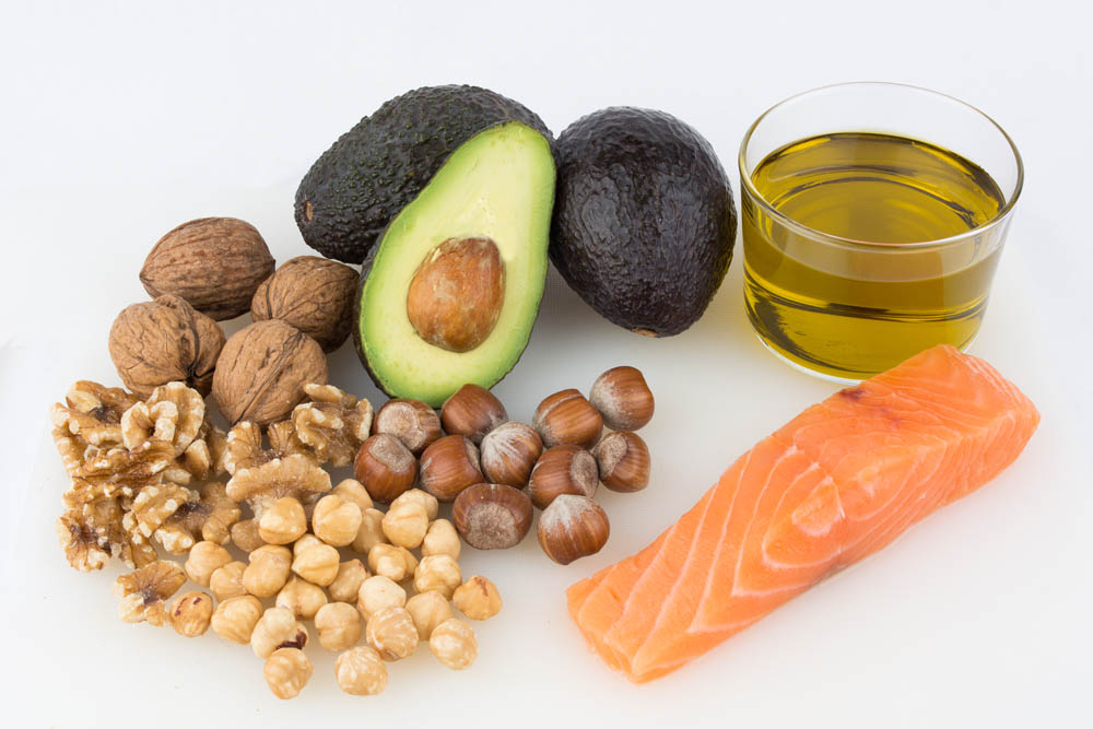 Image of different fats including avocadoes, oil, various nuts and salmon