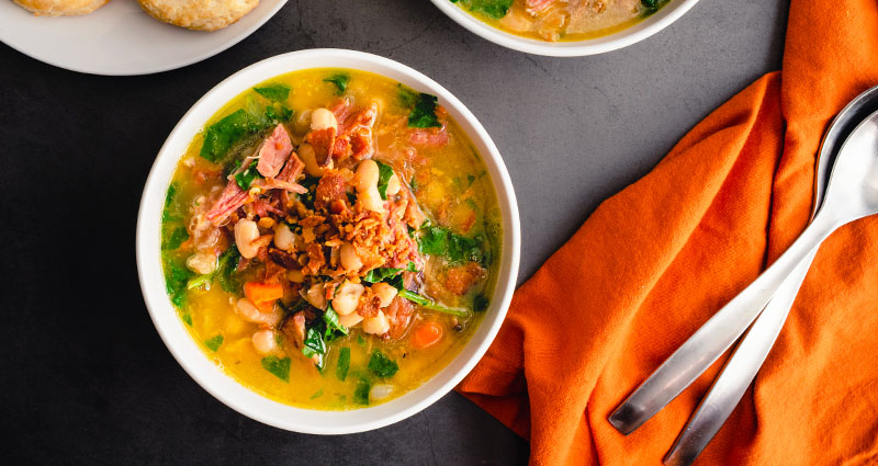 A bowl filled with southern-style soup topped with turkey bacon.