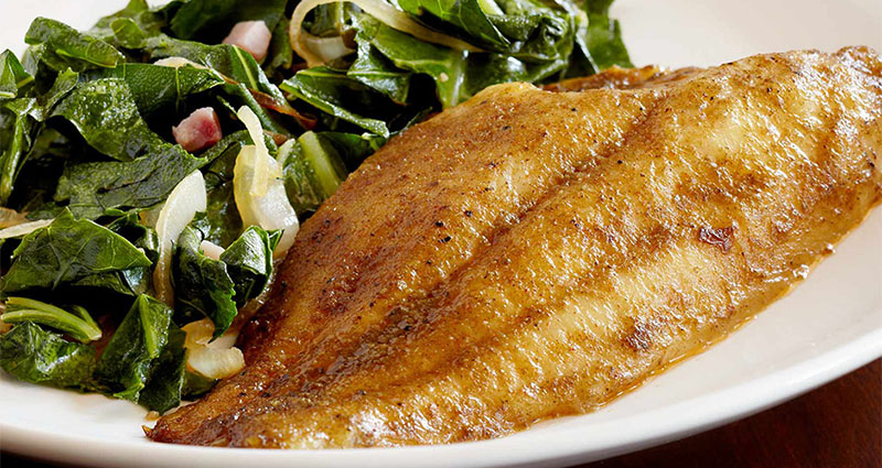 Baked white fish served with collard greens
