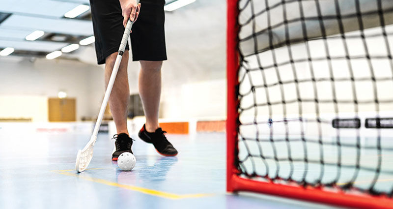 A man playing ball hockey, ready to score a goal