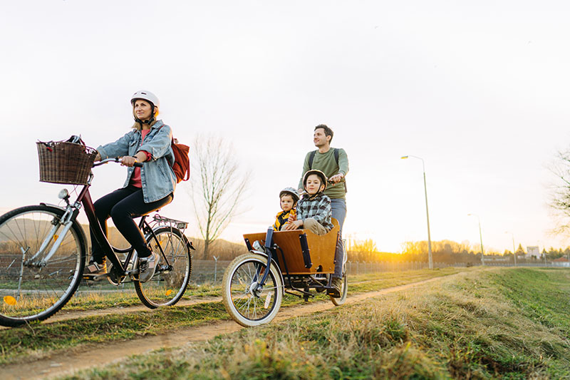 A cheerful young family with two children who enjoys bicycle ride together, on a sunny springtime day