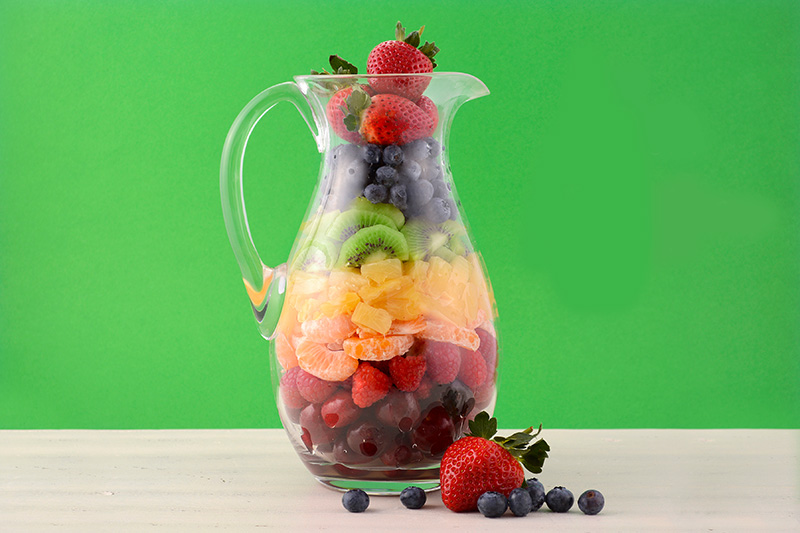 A pitcher on a table full of layered fruits to make a delicious sangria.