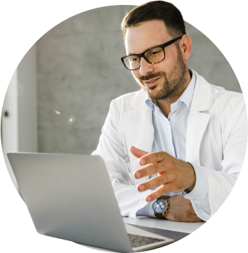Male doctor wearing glasses having a virtual consultation on a laptop.