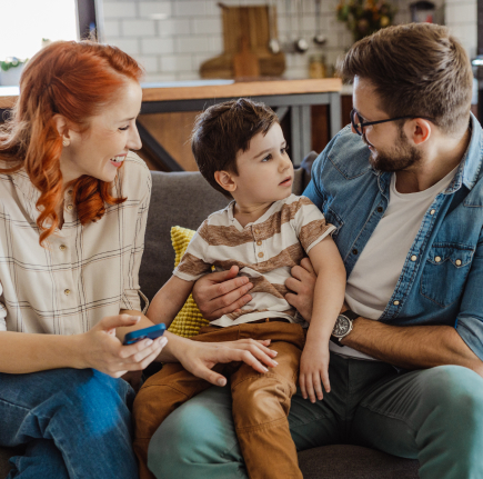 Mother and father sitting on couch with father holding child on his knee