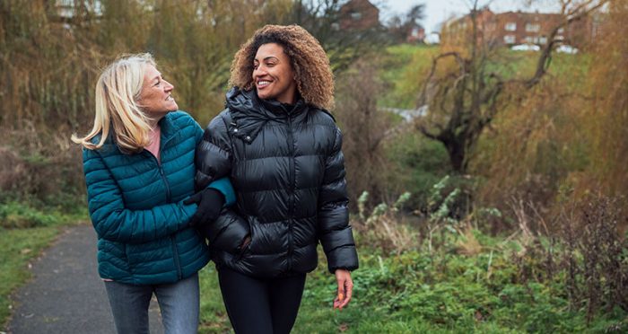 Two happy women taking a walk outside wearing puffy winter coats