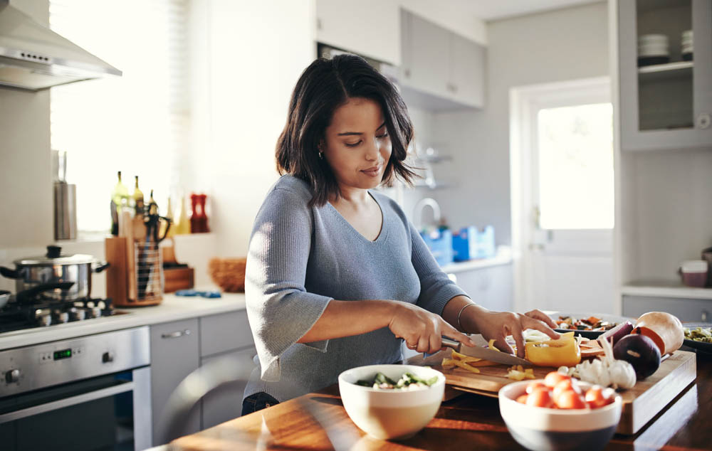 Woman preparing vegetables in a bright kitchen