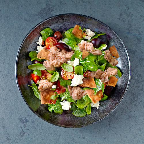Cherry tomato and spinach salad with artichoke hearts, kalamata olives and feta cheese. Mediterranean cuisine. Flat lay