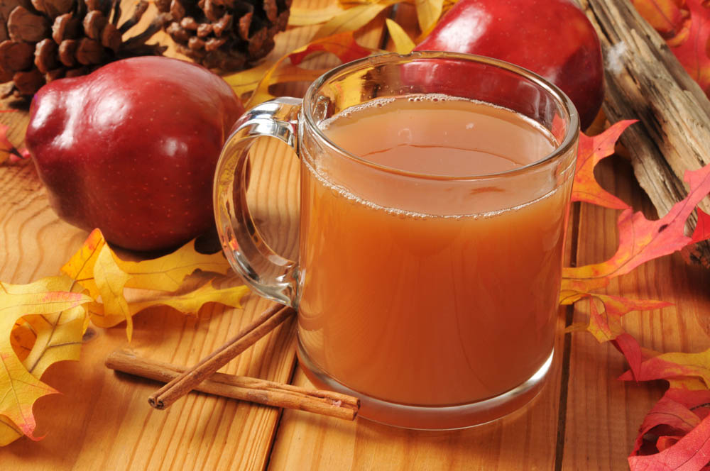 A cup of hot apple cider on an autumn table setting