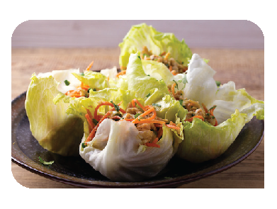 Lettuce wraps filled with shredded carrots, chopped vegetables, and a protein mix served on a dark plate on a wooden surface.