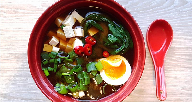 Bowl of ramen with tofu, vegetables, and a soft-boiled egg.
