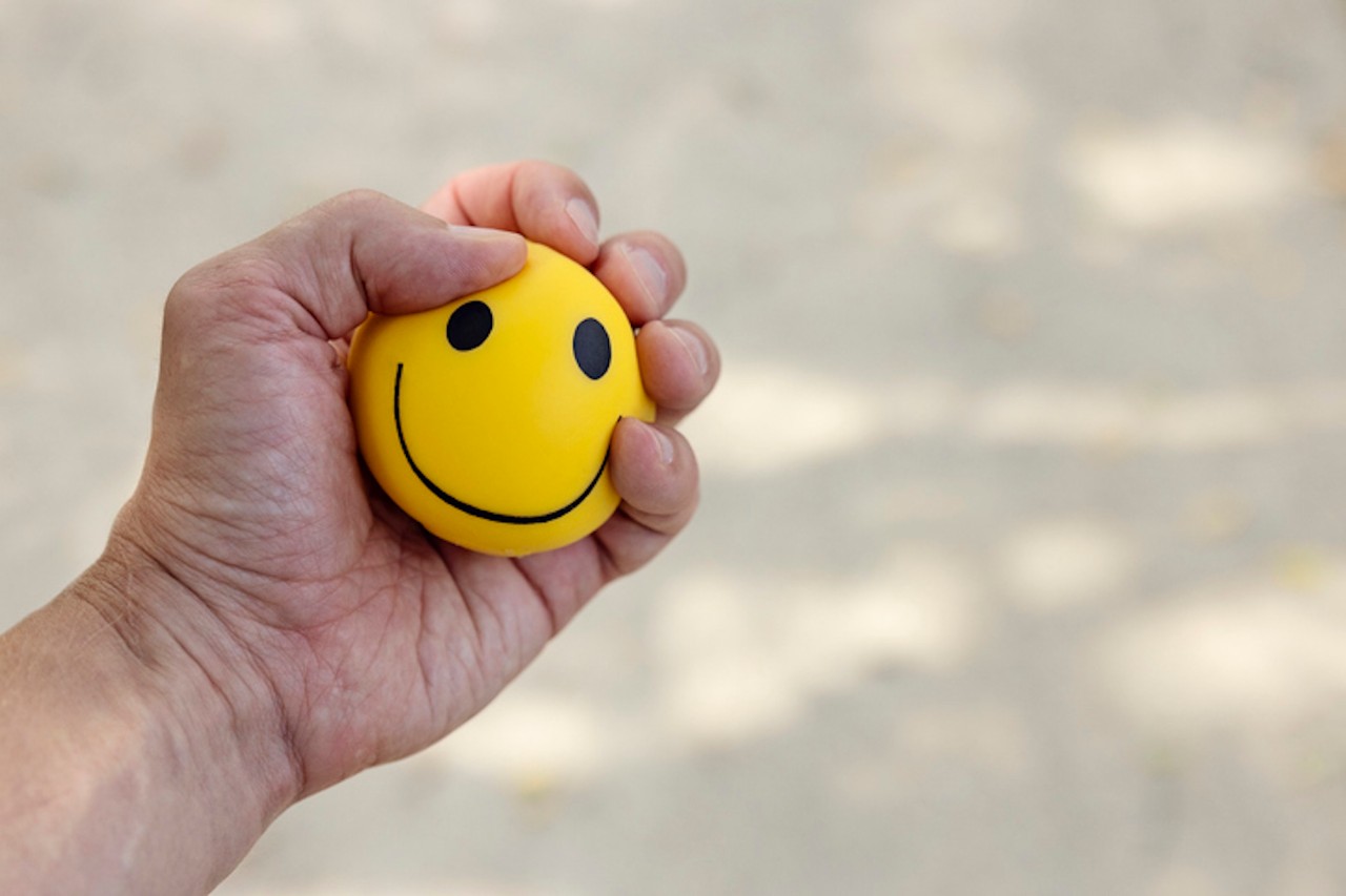 Hand squeezing a yellow smiley stress ball