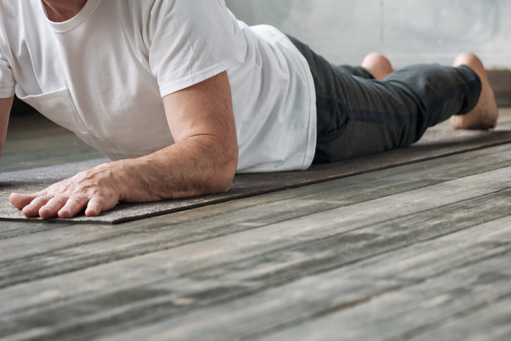 Yoga man in Cobra or sphinx pose bhujangasana variation in the gym. No face view.