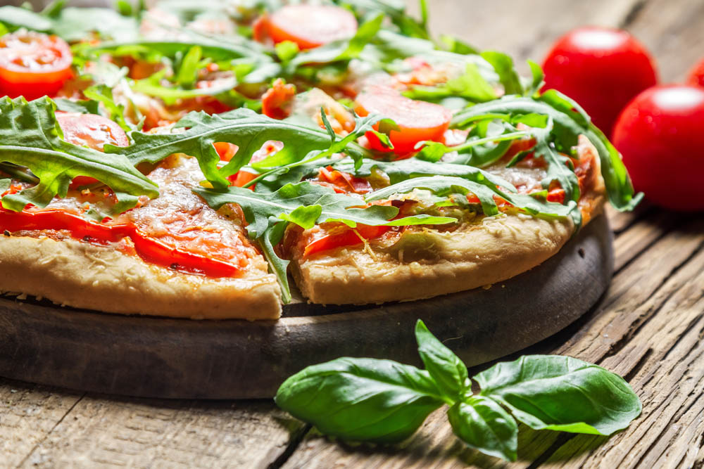 Closeup of freshly baked pizza with basil and tomatoes