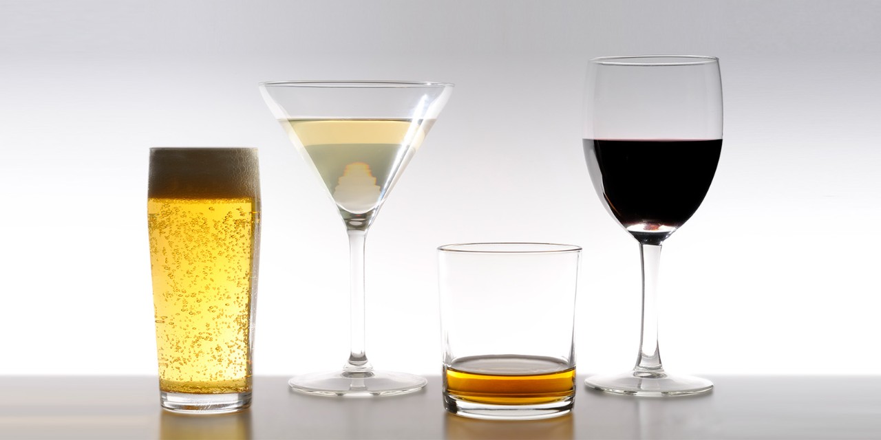 Four glasses with different beverages: a tall beer glass, a martini glass with white liquid, a short glass with amber liquid, and a wine glass with red wine.