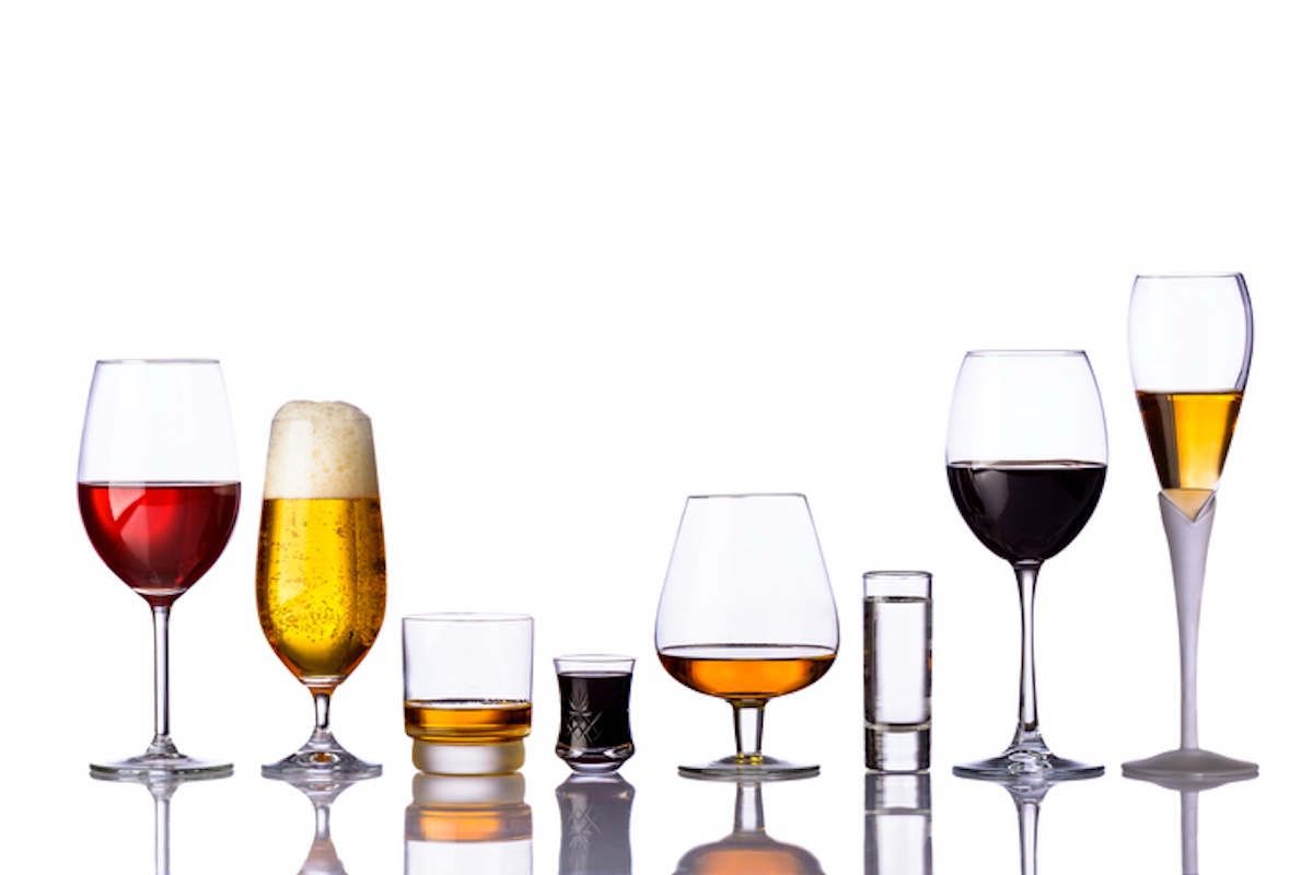A variety of drink glasses lined up, including wine glasses, a beer glass, a shot glass, and a cocktail glass, all against a white background.
