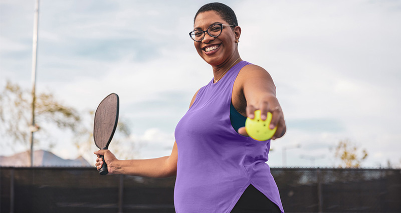 Woman holding pickleball and paddle