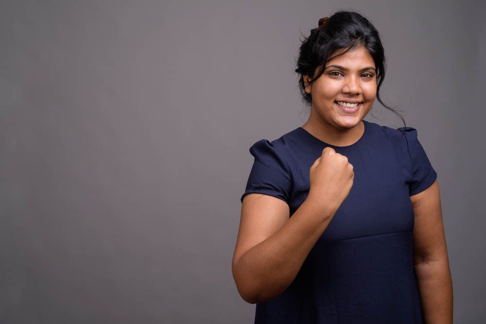 Studio shot of young overweight beautiful Asian woman against gray background