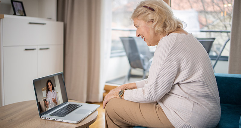 Elderly woman having a virtual consultation with a doctor on her laptop at home.