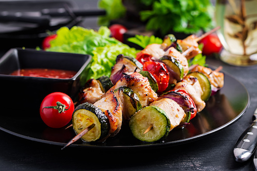 Grilled meat skewers, chicken  shish kebab with zucchini, tomatoes and red onions. Barbecue food.