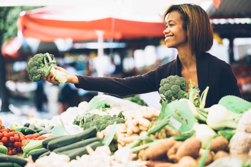 Young woman buying vegetables at farmers market