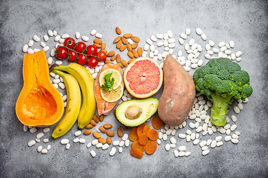 Vegetables, fruit and foods containing potassium over gray stone background, top view. Natural sources of potassium, vitamins and micronutrients for healthy balanced diet and avitaminosis prevention