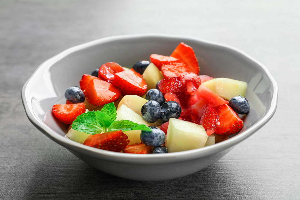 Bowl with yummy fruit salad on grunge table