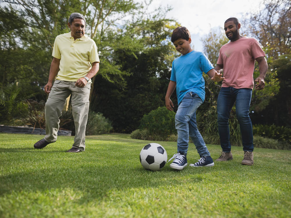  A joyful scene of three people playing soccer on a grassy lawn.