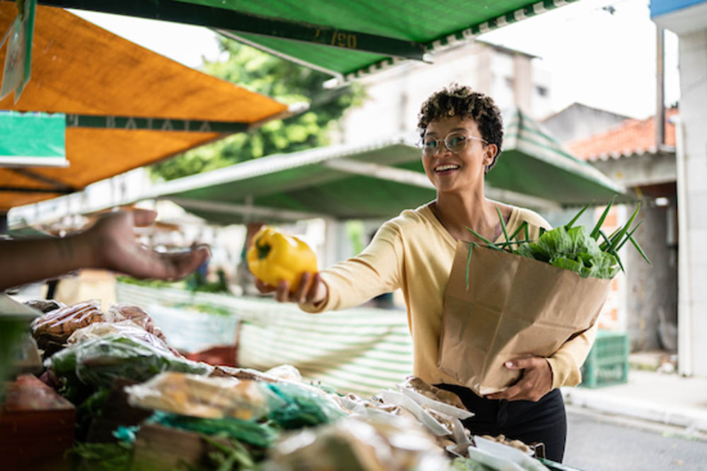 Young woman buying a bell pepper seller at a street market
