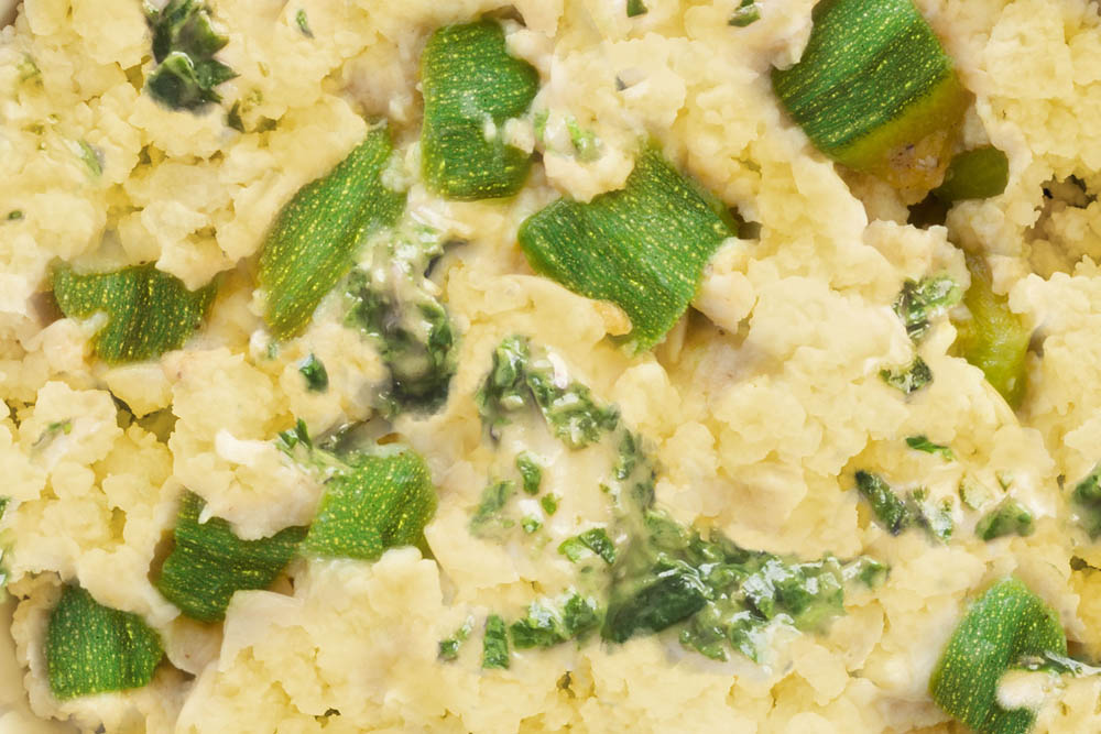 A close-up of scrambled eggs with zucchini and herbs.