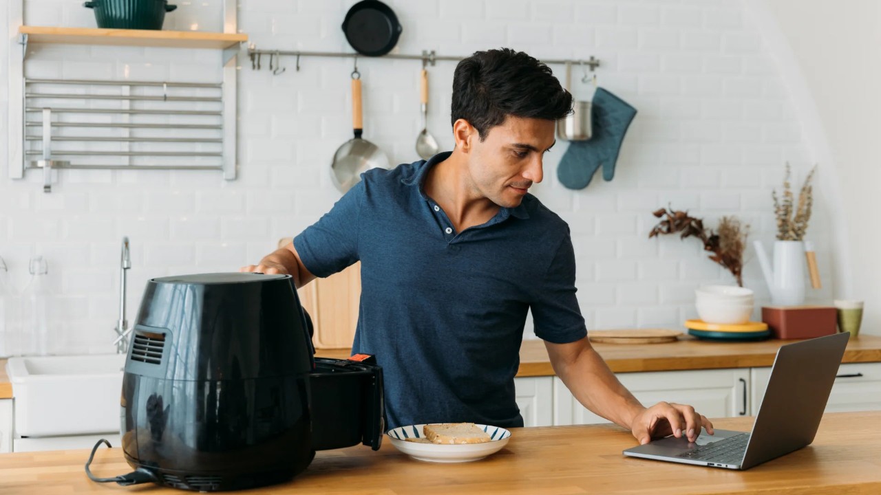 Man with airfryer and computer recipe
