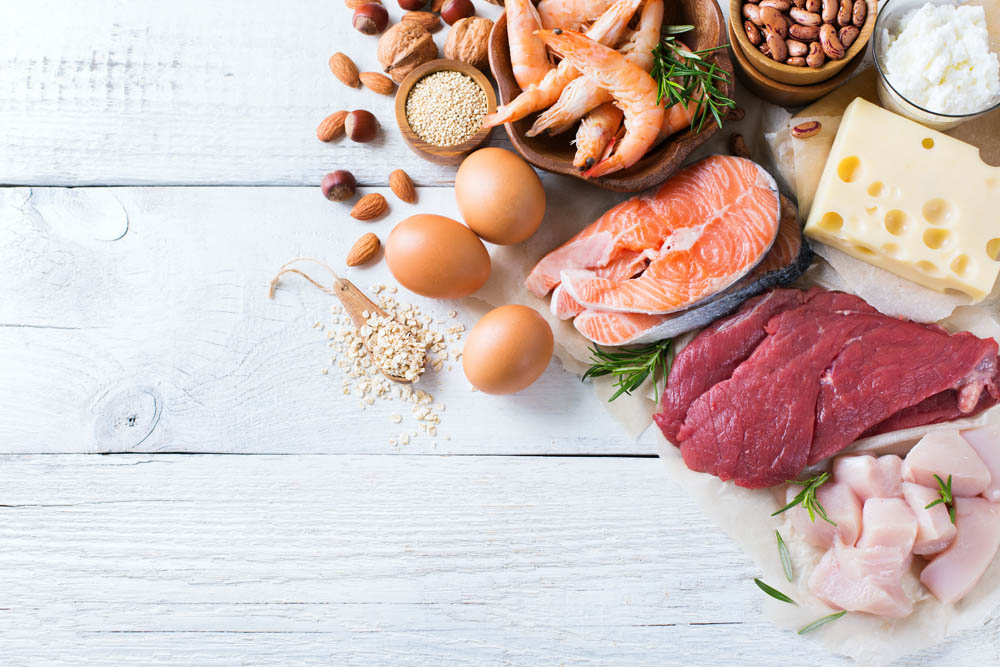 Assortment of healthy protein source and body building food. Meat beef salmon chicken eggs dairy products milk cheese yogurt beans quinoa nuts oat meal. Copy space background, top view flat lay