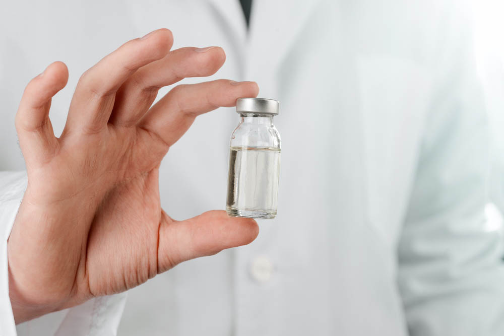 Scientist holding a vial of new vaccine, close up. Medicine development and health care.