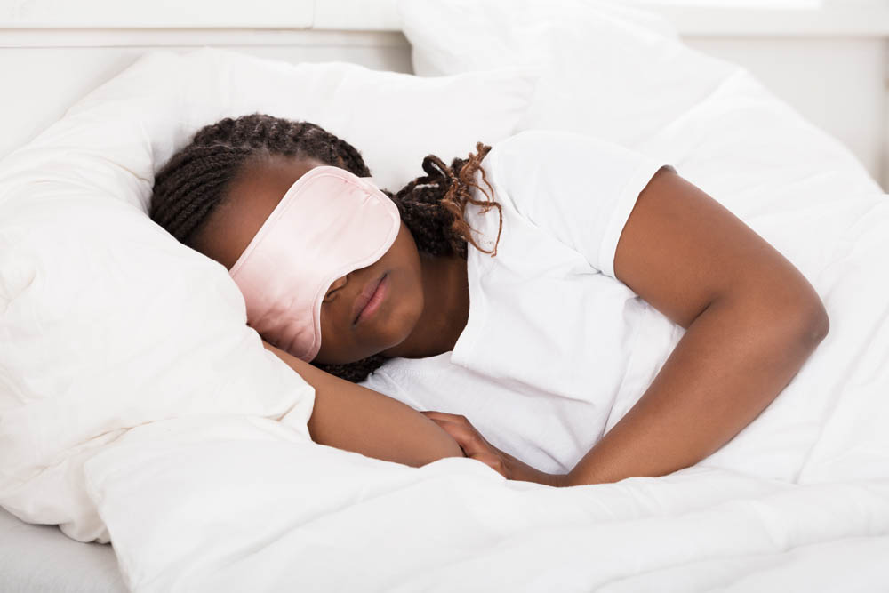Close-up Of An African Girl With Pink Eye Mask Sleeping In Bed