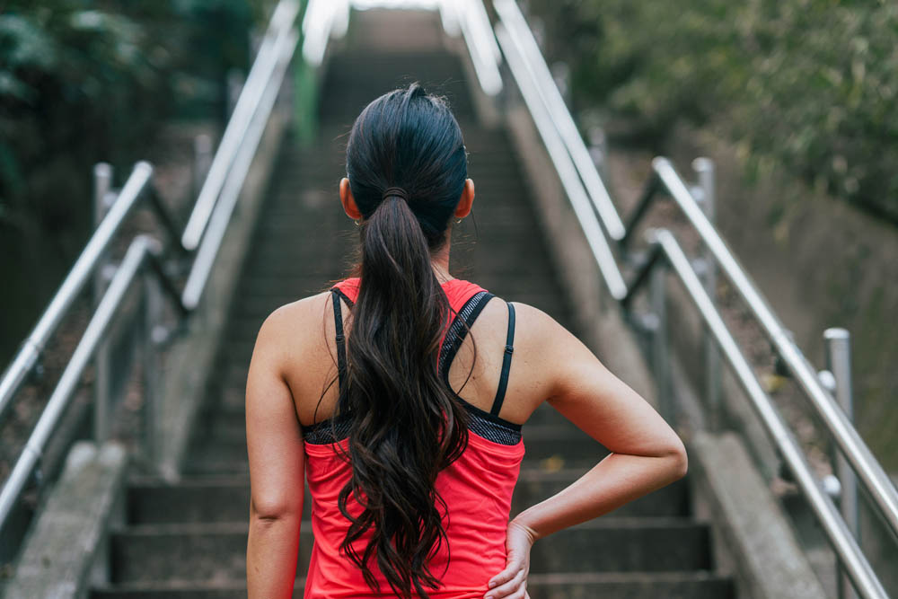 A rear view of a female athlete in front of steps.
