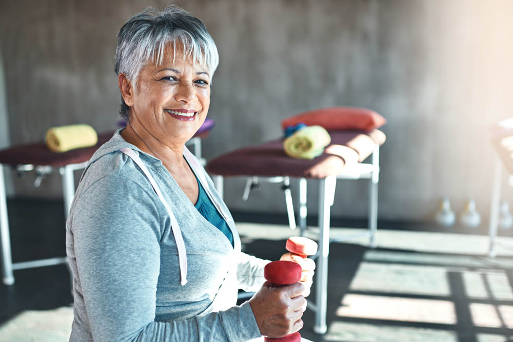 Portrait of a happy senior woman working out with weights