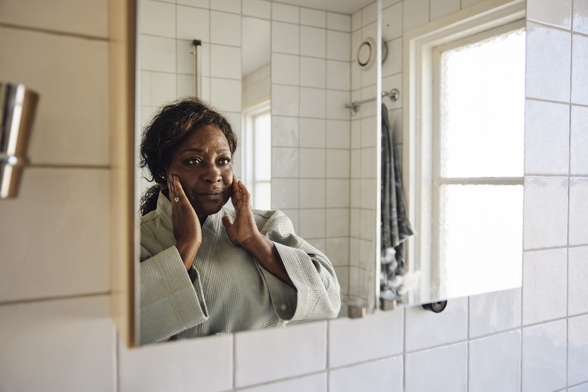 Woman looking at herself in the bathroom mirror
