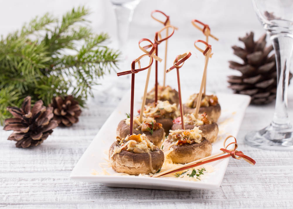 Stuffed mushrooms on white plate. Served on a festive table. Wooden background.