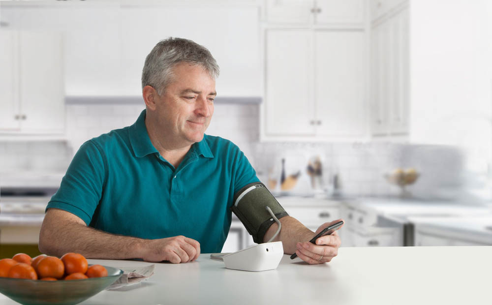 Man checking his blood pressure at home using a monitor.