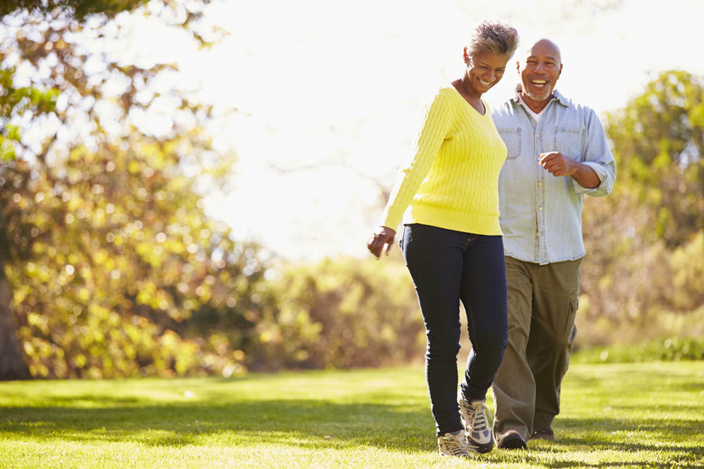 Smiling senior couple walking together in a sunny park.