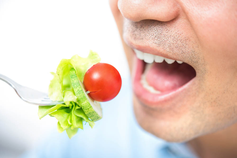 Young man eating healthy salad, close up