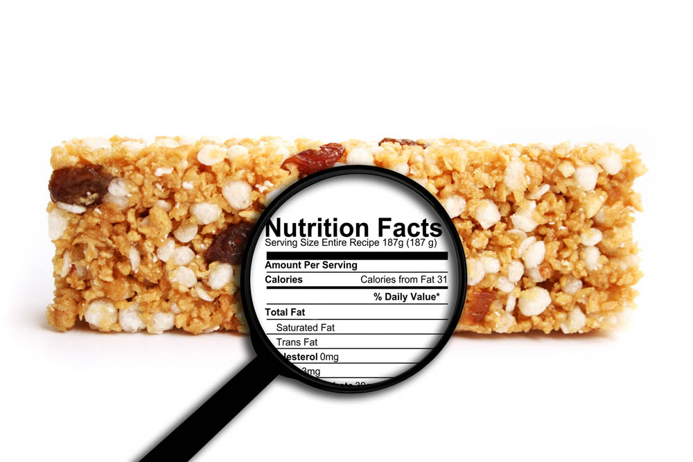 Granola bar with a magnifying glass highlighting the nutrition facts label.