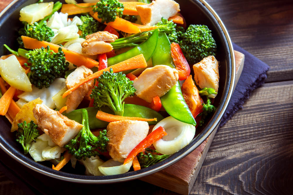 Healthy stir fried vegetables with chicken on pan close up