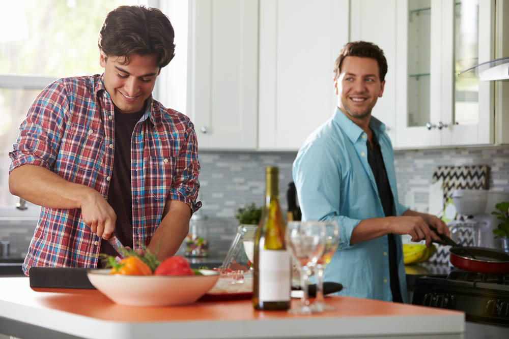 Male gay couple preparing a meal together in the kitchen