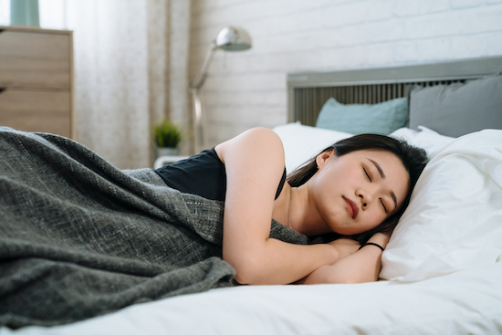 Shot of lovely asian chinese girl has pleasant dreams and health sleep in white bed. young smiling woman having good rest during weekends. Sleeping female in cozy sunny bedroom in morning at home.