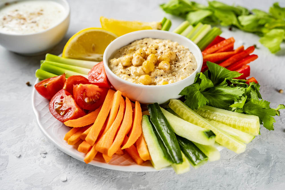 A plate with colorful healthy sliced vegetables and dips. Close up. Healthy vegetarian food