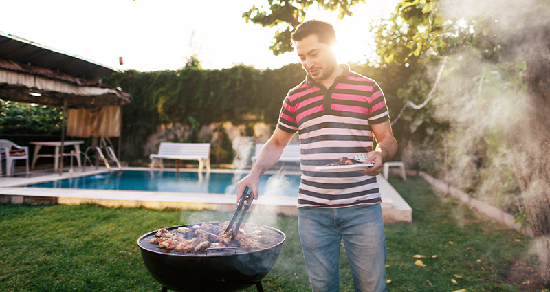 A man grilling in a backyard ready to serve food