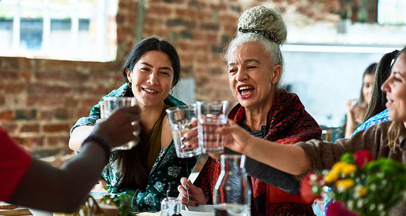 Group of friends toasting with glasses of water at a restaurant.