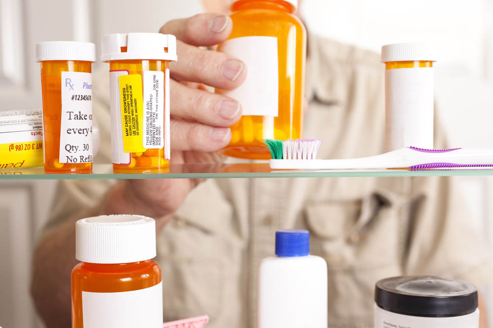 Man taking prescription pills out of medicine cabinet 