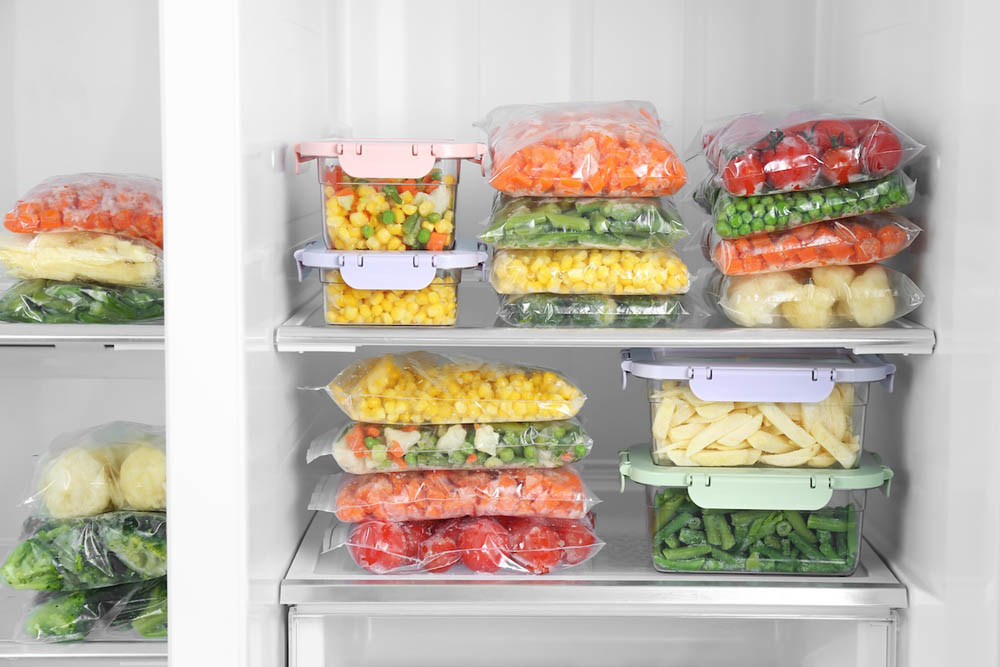 An organized refrigerator interior showcasing various containers filled with colorful chopped vegetables and fruits, neatly arranged on multiple shelves.
