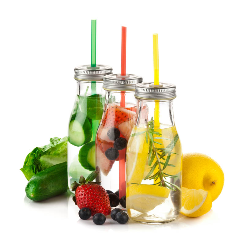 Healthy eating concept: Square shot of three infused water detox drink in glass bottles with fruits and vegetables around them isolated on white background. Predominant colors are yellow, red, green and white. DSRL studio photo taken with Canon EOS 5D Mk II and Canon EF 70-200mm f/2.8L IS II USM Telephoto Zoom Lens
